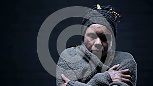 Homeless woman closed eyes suffering cold on dark background, depressed beggar
