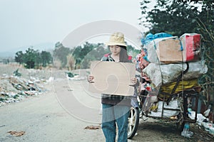 Homeless woman holding sign with hat and backpack standing on a road