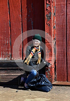 Homeless Woman Kneels by Red Building