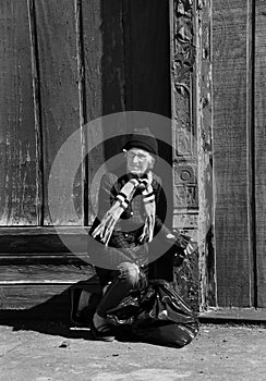 Homeless Woman Kneels by Red Building Black and White