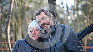 A homeless woman and a man pose in the woods in winter.