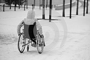 Homeless woman sits in a wheelchair in winter. black and white.