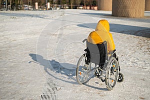 Homeless woman sitting in wheelchair in winter.