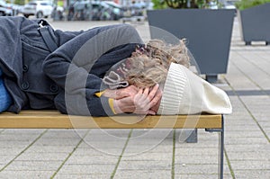 Homeless woman sleeping rough on a bench