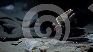 Homeless woman throwing coins from paper cup, counting donations, charity