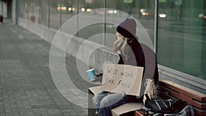 Homeless young man beg for money shaking cup to pay attention people walking near beggar at the city sidewalk