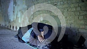 Homeless young man sleeping on street, indifferent egoistic society, poverty