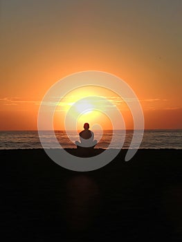man meditating on the beach during the sunrise photo
