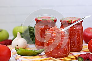 Homemade adzhika with apples in jars on a white background
