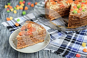 Homemade air-nut cake with chocolate cream, boiled condensed milk, candied fruit, nuts and dried apricot on grey wooden background