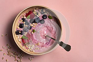 Homemade antioxidant summer fruits oatmeal on light pink background