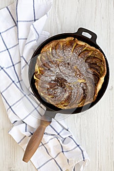 Homemade Apple Dutch Pannekoek Pancake in a cast-iron pan on a white wooden background, top view. Overhead, from above, flat lay