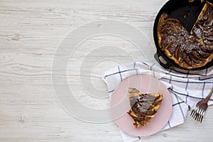 Homemade Apple Dutch Pannekoek Pancake in a cast-iron pan on a white wooden table, top view. Copy space