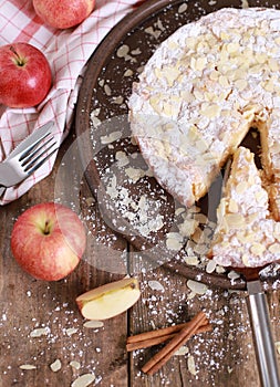 Homemade apple pie - on a plate with fresh apples and cinnamon sticks on a rustic wooden table