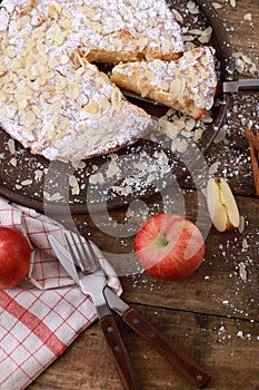 Homemade apple pie - on a plate with fresh apples and cinnamon sticks on a rustic wooden table