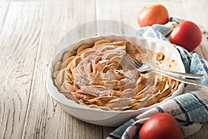 Homemade apple pie on a white wooden background near the window close-up and copy space. Charlotte in the morning on the table