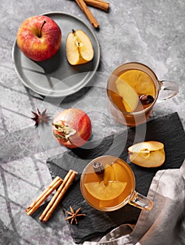 Homemade apple punch with fresh apples, cinnamon and spices in cups on dark background with fresh fruits. A hot, healthy autumn or