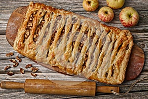 Homemade apple and walnut pie on a wooden board surrounded by ingredients