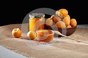 Homemade apricot jam in glass jars. Fresh apricots on the table around jars of orange jam