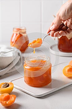 Homemade apricot jam in spoon in woman& x27;s hand.