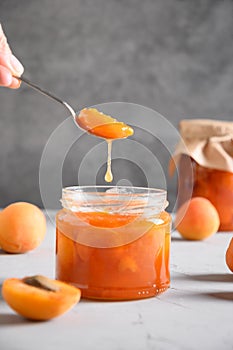 Homemade apricot jam in spoon in woman's hand.