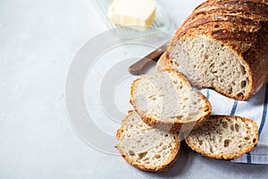 Homemade artisanal sliced sourdough bread on a napkin and butter with knife. Healthy home baking concept