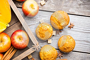 Homemade atutumn muffins with pumpkin, apples and spices on the rustic background