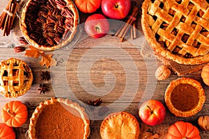 Homemade autumn pie frame over a rustic wood background. Apple, pumpkin and pecan.