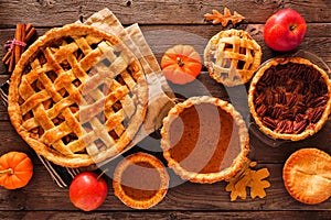 Homemade autumn pie table scene over wood. Apple, pumpkin and pecan.