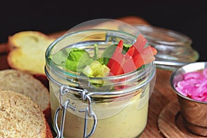 Homemade avocado mask paste in a glass jar with vegetables inside. Prepared from mashed avocado and olive oil.