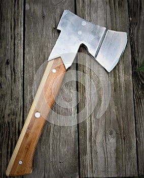 Homemade ax with rivets and wooden handle lies on old planed wooden boards