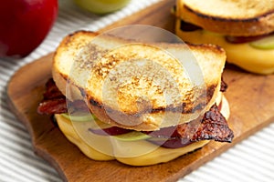 Homemade Bacon Apple Grilled Cheese on a rustic wooden board, low angle view. Close-up