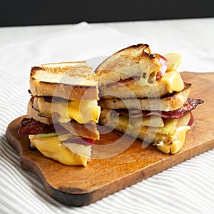 Homemade Bacon Apple Grilled Cheese on a rustic wooden board, low angle view. Close-up