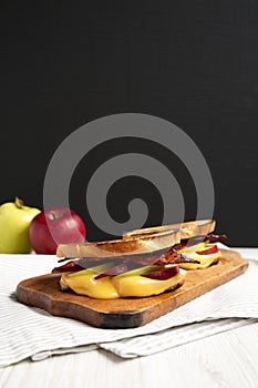 Homemade Bacon Apple Grilled Cheese on a rustic wooden board, low angle view. Copy space