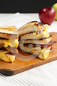 Homemade Bacon Apple Grilled Cheese on a rustic wooden board, side view. Close-up