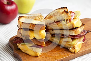 Homemade Bacon Apple Grilled Cheese on a rustic wooden board, side view. Close-up