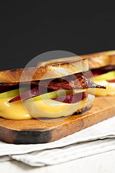 Homemade Bacon Apple Grilled Cheese on a rustic wooden board, side view. Close-up