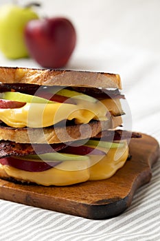 Homemade Bacon Apple Grilled Cheese on a rustic wooden board, side view. Close-up