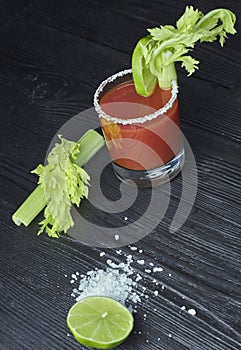 Cocktail Spicy Vodka Bloody Mary with tomatoes and celery on a black table with celery leaves