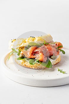 Homemade bagel sandwich with smoked salmon, cream cheese, capers and spinach for healthy breakfast isolated on white