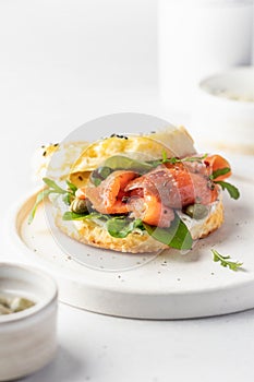 Homemade bagel sandwich with smoked salmon, cream cheese, capers and spinach for healthy breakfast on white kitchen
