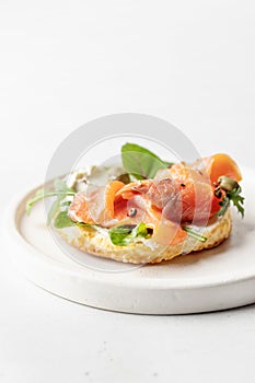 Homemade bagel sandwich with smoked salmon, cream cheese, capers and spinach for healthy breakfast on white kitchen