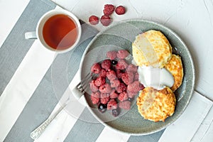 Homemade baked cheesecake on a gray clay plate. Pie with raspberries in small portions, white background