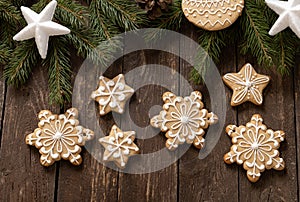 Homemade baked Christmas biscuit cookies with festive icing motives decorating wooden background with conifer branches, winter