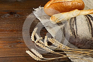 Homemade baked goods and ears of wheat on a wooden background.