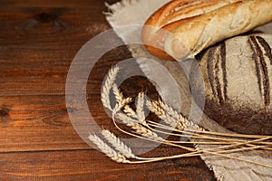 Homemade baked goods and ears of wheat on a wooden background.