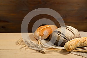 Homemade baked goods and ears of wheat on a wooden background.