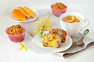 Homemade baked pastries. Healthy pumpkin muffins with traditional fall spices, pieces of pumpkin on saucer. White cup with tea on