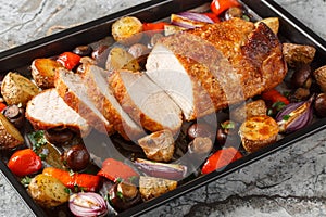 Homemade baked pork loin with vegetables and mushrooms close-up on a baking sheet. Horizontal