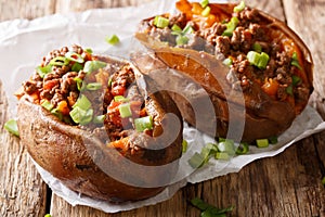 Homemade baked sweet potato stuffed with beef meat and green onions close-up on the table. horizontal